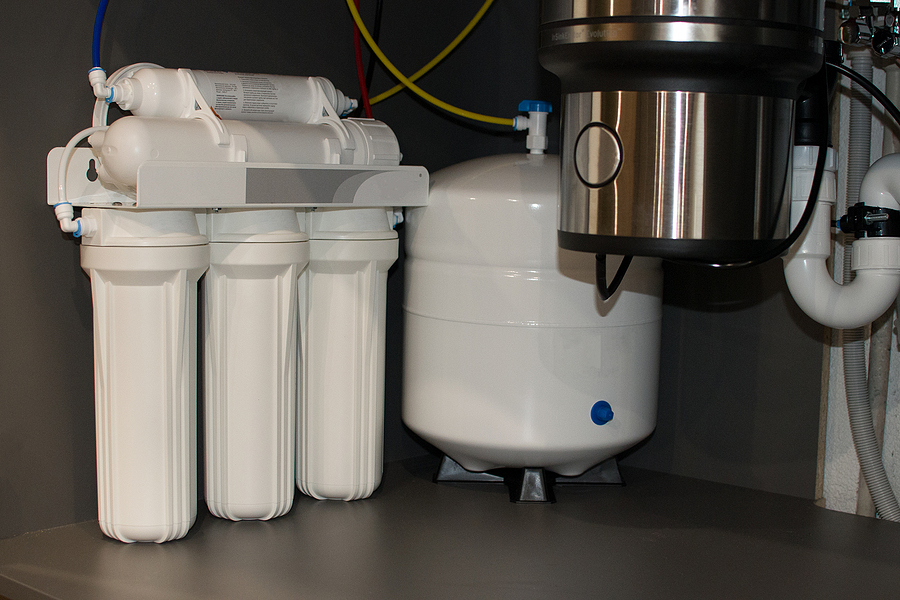 A reverse osmosis water filtration system installed under a kitchen sink.