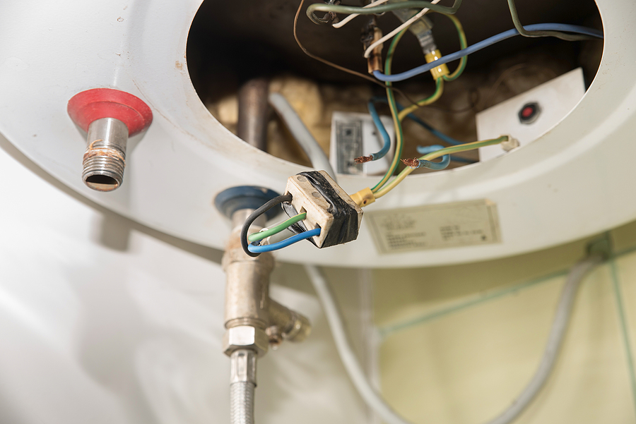 Inside of the broken water heater or boiler with electric wires and pipes.