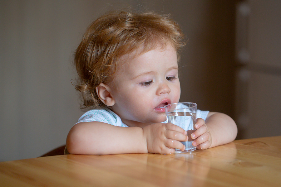 Portrait of a baby drinking water from a glass.